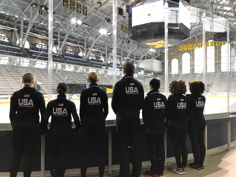 7 Creative Ice Theatre members are wearing their Team USA jackets looking at the ice rink.